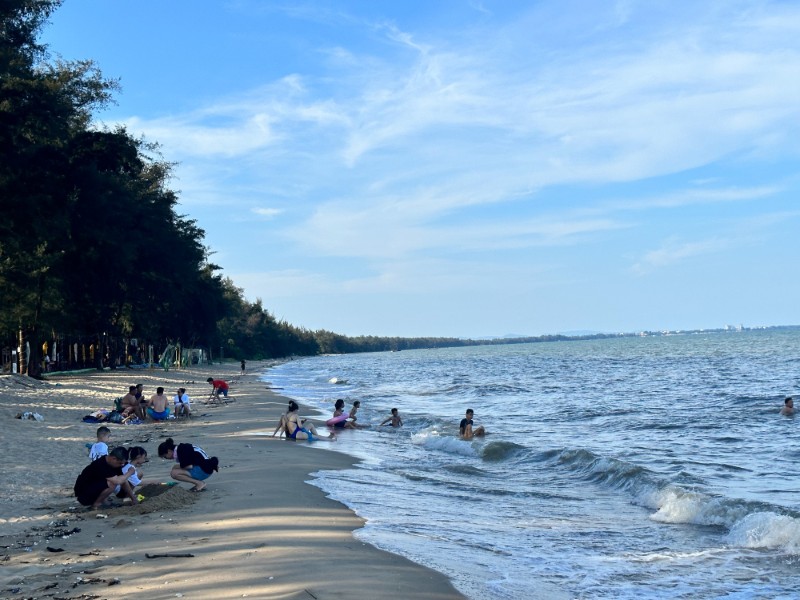 Khung cảnh yên bình của Bãi Đá Đen tại Móng Cái với cây xanh và làn nước trong lành.