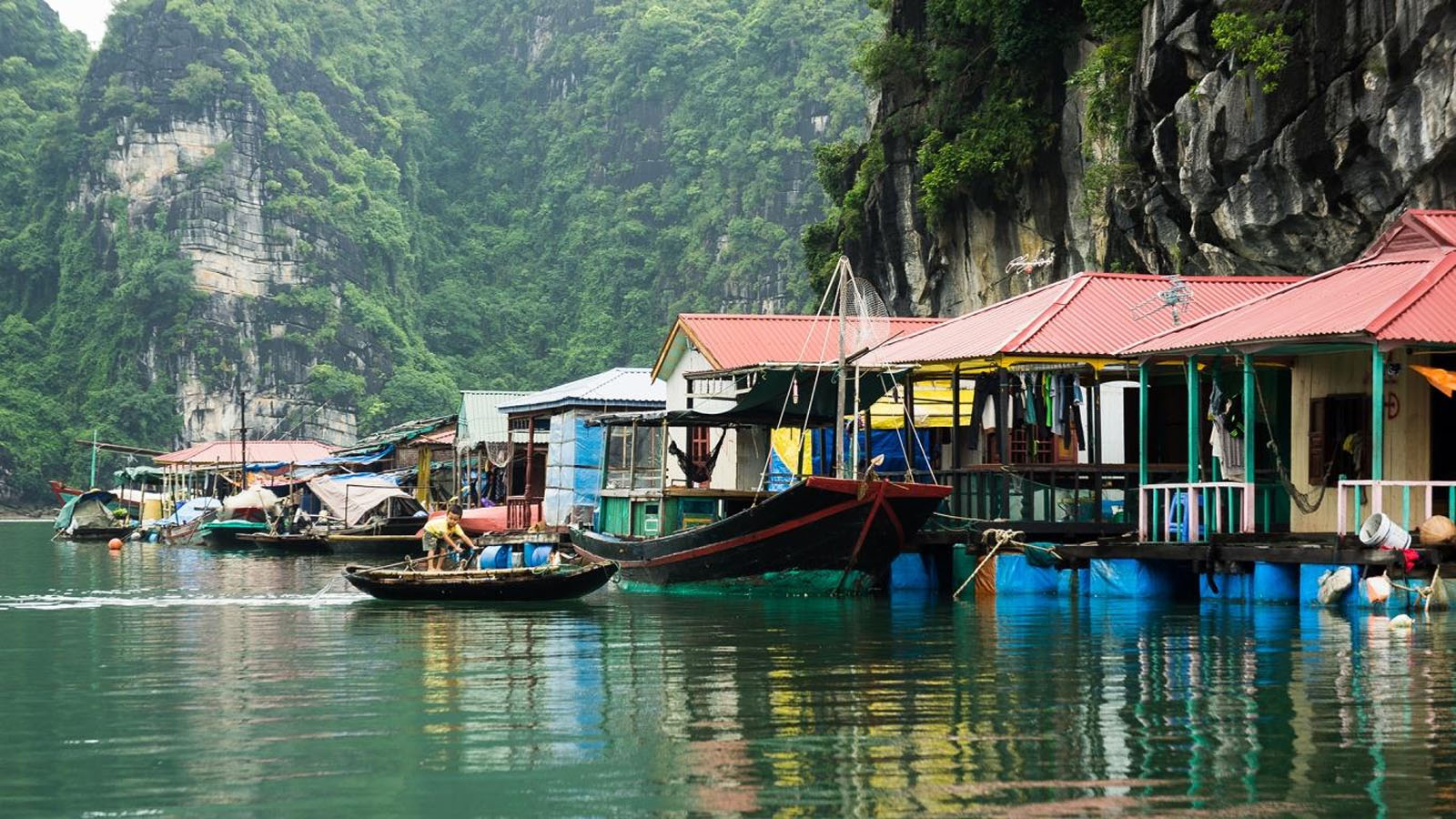 Các thuyền du lịch di chuyển qua Vịnh Hạ Long trên đường đến Làng Ngọc Tùng Sâu, bao quanh bởi các dãy núi đá vôi.