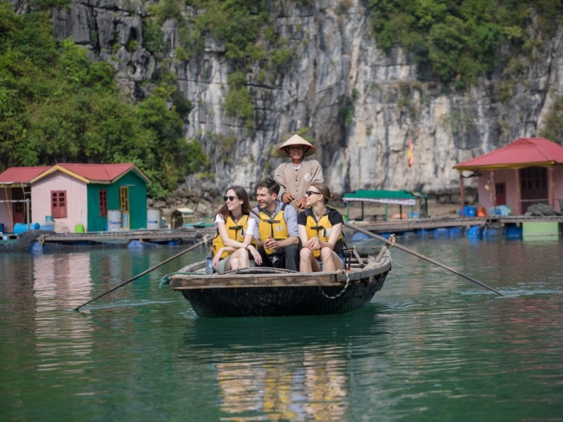 Du khách tận hưởng chuyến đi thuyền tre tại Làng Chài Cửa Vạn, bao quanh bởi vách đá vôi và cây xanh.