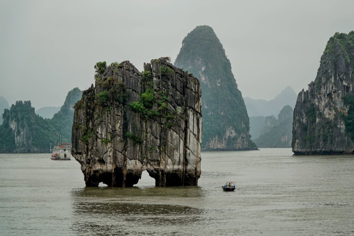 Hòn Đỉnh Hương tại Vịnh Hạ Long, nổi bật với hình dáng độc đáo, được bao quanh bởi nước và núi đá vôi xa xa.