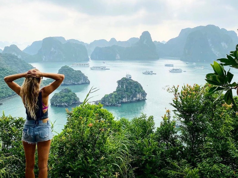 Khám phá cảnh quan Vịnh Bái Tử Long từ Hòn Đầu Mối Cảnh quan Vịnh Bái Tử Long nhìn từ Hòn Đầu Mối với các đảo nhỏ và du thuyền, một phụ nữ đứng chiêm ngưỡng thiên nhiên.