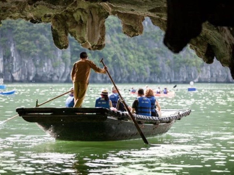 Du khách thưởng ngoạn chuyến đi thuyền tre qua Hang Luồn tại Vịnh Hạ Long, bao quanh bởi vách đá xanh tươi và làn nước ngọc bích.