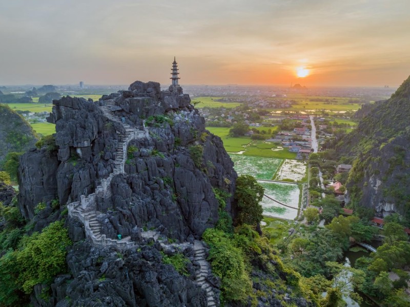 Cảnh chụp từ trên cao của du khách đang leo lên điểm ngắm cảnh Hang Múa ở Ninh Bình, bao quanh bởi thảm thực vật xanh tươi và những dãy núi đá vôi.