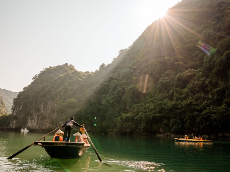 Chuyến đi thuyền tre qua Hang Luồn tại Vịnh Hạ Long, với các vách đá vôi hùng vĩ và làn nước yên ả.