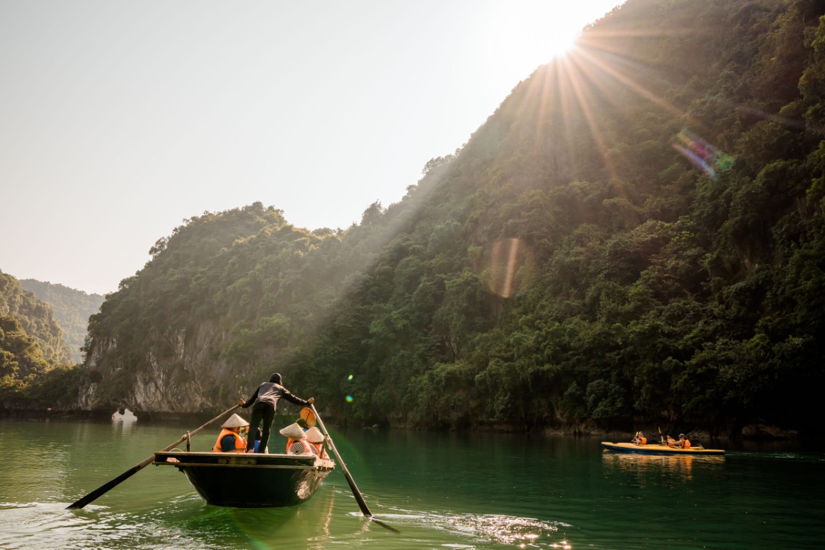 Chuyến đi thuyền tre qua Hang Luồn tại Vịnh Hạ Long, với các vách đá vôi hùng vĩ và làn nước yên ả.