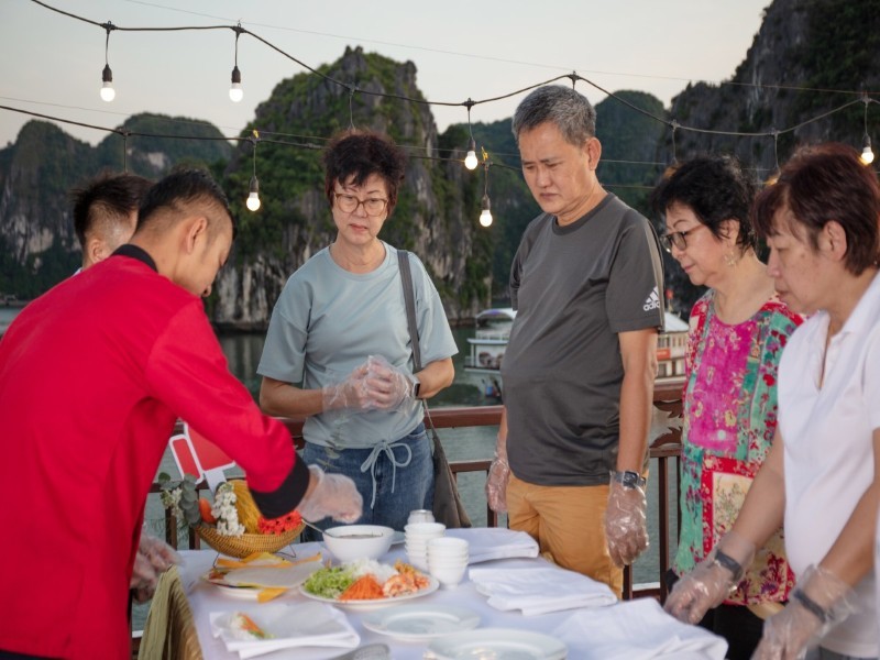 Guests participating in a hands-on Vietnamese cooking class aboard Amanda Cruise.